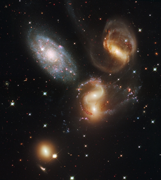 A clash among members of a famous galaxy quintet reveals an assortment of stars across a wide colour range, from young, blue stars to aging, red stars. This portrait of Stephan's Quintet, also known as the Hickson Compact Group 92, was taken by the new Wide Field Camera 3 (WFC3) aboard the NASA/ESA Hubble Space Telescope. Stephan's Quintet, as the name implies, is a group of five galaxies. The name, however, is a bit of a misnomer. Studies have shown that group member NGC 7320, at upper left, is actually a foreground galaxy that is about seven times closer to Earth than the rest of the group. Three of the galaxies have distorted shapes, elongated spiral arms, and long, gaseous tidal tails containing myriad star clusters, proof of their close encounters. These interactions have sparked a frenzy of star birth in the central pair of galaxies. This drama is being played out against a rich backdrop of faraway galaxies. The image, taken in visible and near-infrared light, showcases WFC3's broad wavelength range. The colours trace the ages of the stellar populations, showing that star birth occurred at different epochs, stretching over hundreds of millions of years. The camera's infrared vision also peers through curtains of dust to see groupings of stars that cannot be seen in visible light. NGC 7319, at top right, is a barred spiral with distinct spiral arms that follow nearly 180 degrees back to the bar. The blue specks in the spiral arm at the top of NGC 7319 and the red dots just above and to the right of the core are clusters of many thousands of stars. Most of the Quintet is too far away even for Hubble to resolve individual stars. Continuing clockwise, the next galaxy appears to have two cores, but it is actually two galaxies, NGC 7318A and NGC 7318B. Encircling the galaxies are young, bright blue star clusters and pinkish clouds of glowing hydrogen where infant stars are being born. These stars are less than 10 million years old and have not yet blown away their n